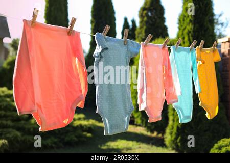 Baby bodysuits drying on washing line outdoors Stock Photo