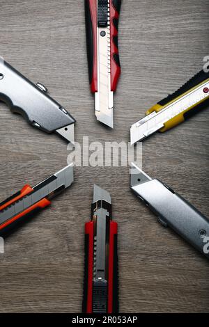 Many different utility knives on wooden table, flat lay Stock Photo
