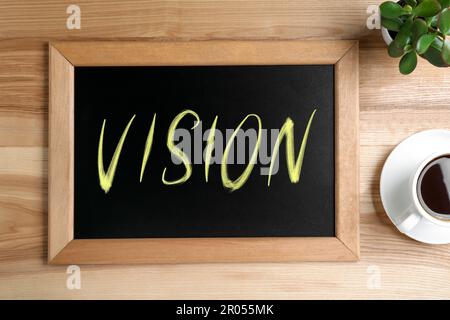 Small chalkboard with word Vision, coffee and plant on wooden table, flat lay Stock Photo