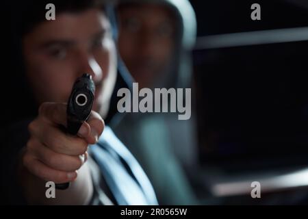 Dont move. two men sitting in a car and pointing a gun. Stock Photo