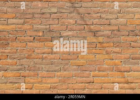 Abstract texture background of a vintage orange brick wall with weathered bricks and a single faint line shadow in sunlight Stock Photo