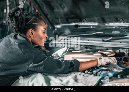 Experienced auto mechanics inspect car battery terminals and voltage to