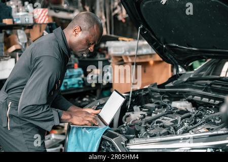 Experienced auto mechanics inspect car battery terminals and voltage to