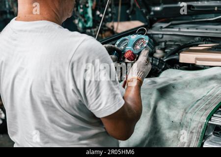 Experienced auto mechanics inspect car battery terminals and voltage to