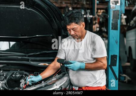 Experienced auto mechanics inspect car battery terminals and voltage to