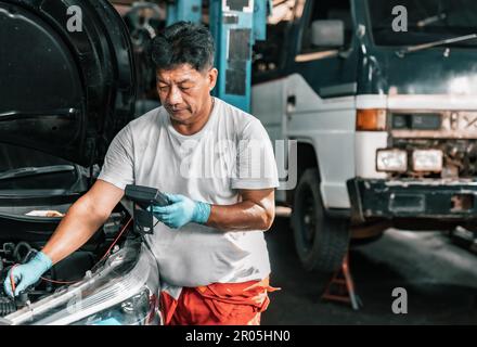Experienced auto mechanics inspect car battery terminals and voltage to