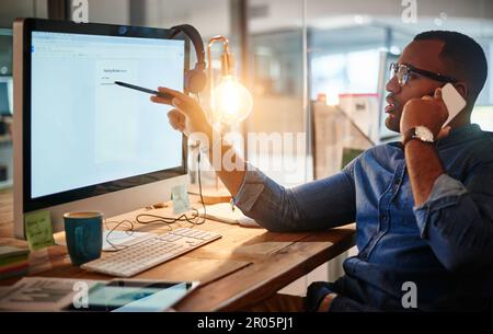 Im just reviewing the minutes of the meeting. a young businessman talking on his phone and using a computer during a late night at work. Stock Photo