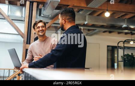 Two business men talking to each other about their tech work. business colleagues discussing efficient ideas to finish a project. Male professionals w Stock Photo