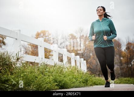 Her fitness comes first. an attractive young woman going for a run in nature. Stock Photo