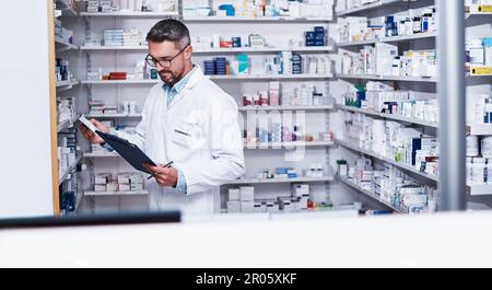 He knows his drugs. a mature pharmacist doing inventory in a pharmacy. Stock Photo