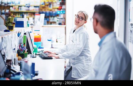 They work well alongside each other. two pharmacists working in a pharmacy. Stock Photo