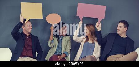 We all have something to say for the interview. a group of businesspeople holding up speech bubbles while waiting in line for an interview. Stock Photo