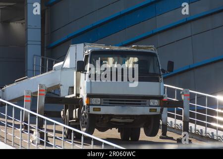 Hydraulics crane support. Small crane truck with outriggers on a sloping road ramp Stock Photo