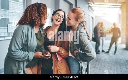 Stopping for a laugh in between lectures. a group of young students using a smartphone together outdoors on campus. Stock Photo