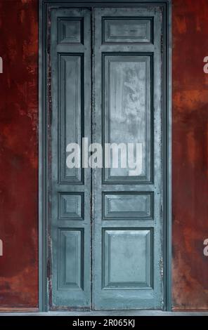 Vintage teal green wooden door on dark red exterior wall. Retro interior concept with copy space. Stock Photo