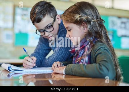 Getting some help from a fellow classmate. two elementary school kids working together in class. Stock Photo