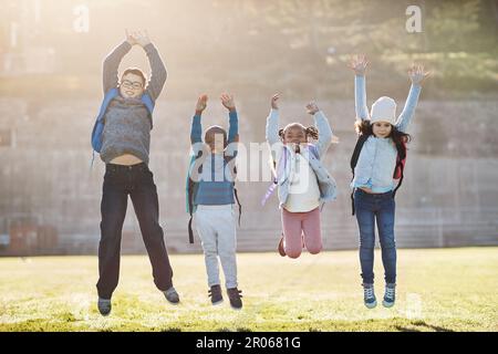 Schools out, time to have fun. Full length portrait of a group of elementary school kids jumping outside. Stock Photo