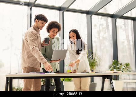 Team Of Coworkers Using Laptop Engaging In Teamwork In Office Stock Photo