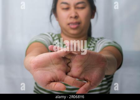 Woman stretching arms sitting at home office desk in wrong position. Tired woman stretching after long working day. Stock Photo