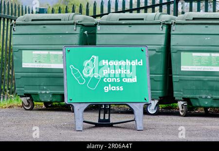 Household plastics, cans and glass recycling containers and sign Stock Photo
