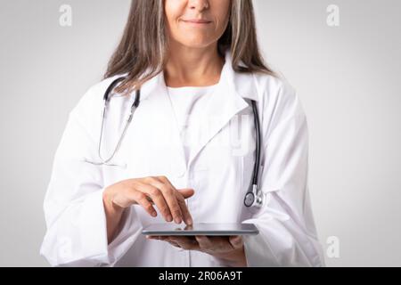 Professional woman doctor physician using digital tablet, reviewing medical record, digital document, cropped, closeup Stock Photo