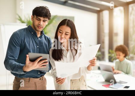 Two diverse business people using tablet interacting working in office Stock Photo