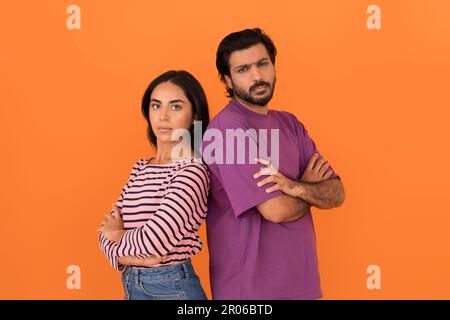 Upset indian couple standing back to back on orange background Stock Photo