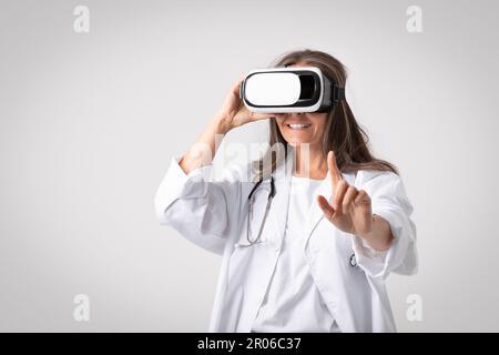 VR medicine concept. Senior woman doctor using modern virtual reality headset for medical purposes, free space Stock Photo