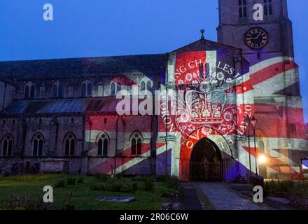 Christchurch, Dorset, UK. 6th May, 2023. Christchurch's Coronation Light Display with special images and animation celebrating the Coronation of King Charles III projected on to the front of Christchurch Priory, created by Light Art Creatives in collaboration with Event Temps UK. Crowds flock to the Priory on a misty murky evening to see reminders of this historic event - the first time Christchurch Priory has hosted a projected light display. Credit: Carolyn Jenkins/Alamy Live News Stock Photo