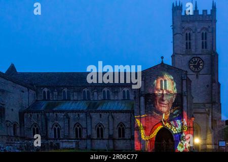 Christchurch, Dorset, UK. 6th May, 2023. Christchurch's Coronation Light Display with special images and animation celebrating the Coronation of King Charles III projected on to the front of Christchurch Priory, created by Light Art Creatives in collaboration with Event Temps UK. Crowds flock to the Priory on a misty murky evening to see reminders of this historic event - the first time Christchurch Priory has hosted a projected light display. Credit: Carolyn Jenkins/Alamy Live News Stock Photo