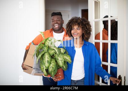Real Estate Purchase. Happy Black Couple Entering Home, Carrying Boxes With Belongings Stock Photo