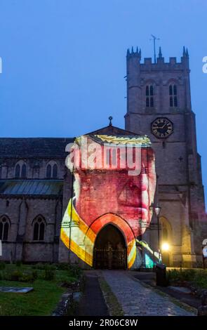 Christchurch, Dorset, UK. 6th May, 2023. Christchurch's Coronation Light Display with special images and animation celebrating the Coronation of King Charles III projected on to the front of Christchurch Priory, created by Light Art Creatives in collaboration with Event Temps UK. Crowds flock to the Priory on a misty murky evening to see reminders of this historic event - the first time Christchurch Priory has hosted a projected light display. Credit: Carolyn Jenkins/Alamy Live News Stock Photo