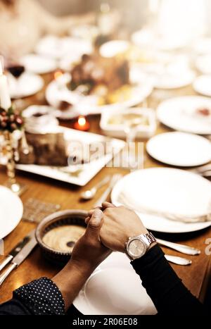 Christmas, a reminder of our blessings. unrecognizable people holding hands in prayer before having a Christmas lunch together. Stock Photo
