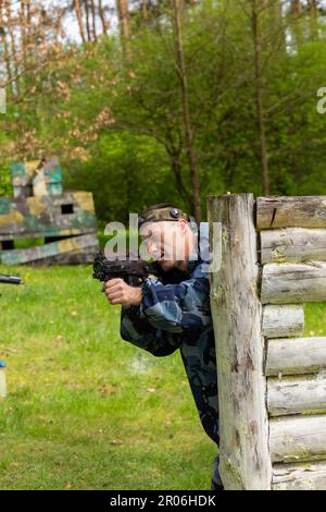 Young man weared in camouflage playing laser tag in special forest playground. Laser Tag is a command military tactical game using safe laser weapons Stock Photo