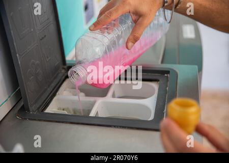 A man pours detergent for washing clothes into the washing machine in a laundromat. Stock Photo
