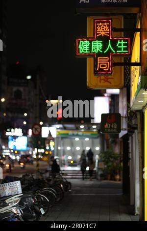 A street sign with neon lights near a parking lof with various motorcycles at night Stock Photo