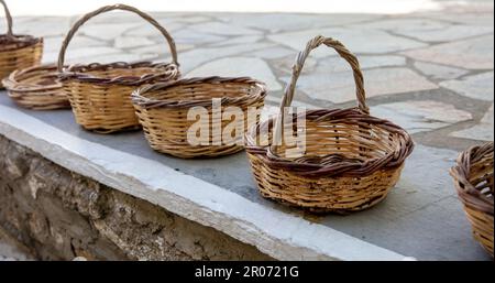 Woven handmade basket for sales on paved street at Cyclades island, Greece. Traditional eco low container from natural rattan with or without handle. Stock Photo