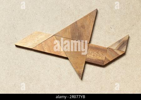 Wooden tangram in flying plane shape on wood background Stock Photo