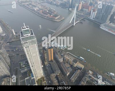 Marvel at the striking contrast between the iconic Erasmus bridge and towering skyscrapers in a stunning aerial drone photo of Rotterdam's skyline. Stock Photo