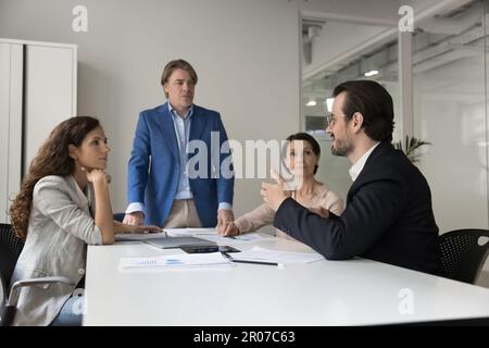 Young successful businessman giving speech to colleagues in office Stock Photo