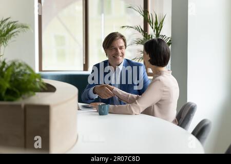 Mature 55s businesspeople shake hands making profitable commercial deal Stock Photo