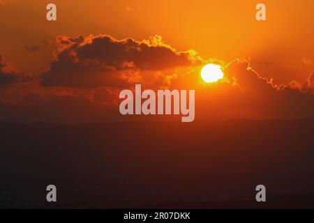 The sun is setting over the clouds in the sky Stock Photo