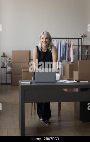 Happy successful mature small business owner woman posing at workplace Stock Photo
