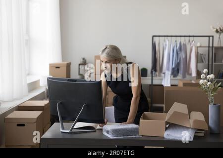 Serious mature internet store owner using desktop in storage place Stock Photo