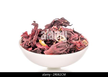 Karkade tea in white ceramic saucer, macro, isolated on white background. Stock Photo