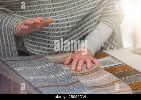 An elderly woman sells knitted items of her own production. Small business concept. Stock Photo