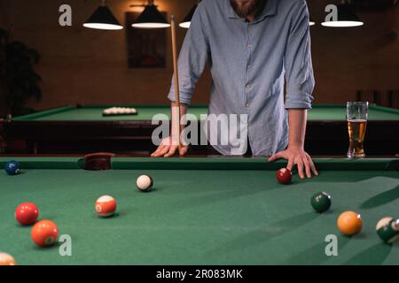 Unrecognizable thoughtful man plays billiards with balls and cue. Billiard room on the background. Billiards concept Stock Photo