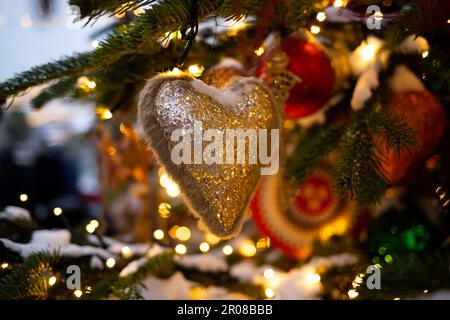 beautiful multi-colored toys on a Christmas tree against the background of lights and snow Stock Photo