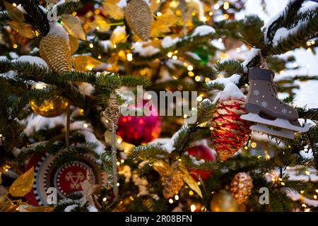 beautiful multi-colored toys on a Christmas tree against the background of lights and snow Stock Photo