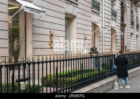 young girls wait in front of a luxury store from Yves Saint